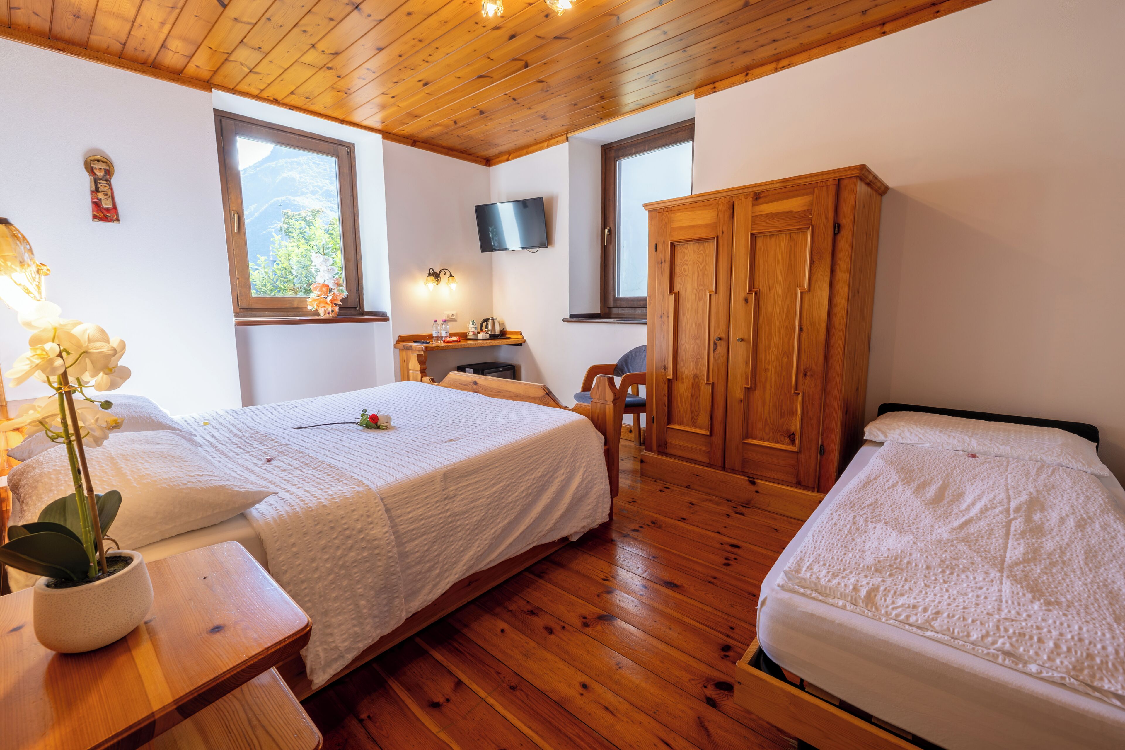 Un dormitorio con dos camas, suelo de madera, un televisor y un armario de madera.