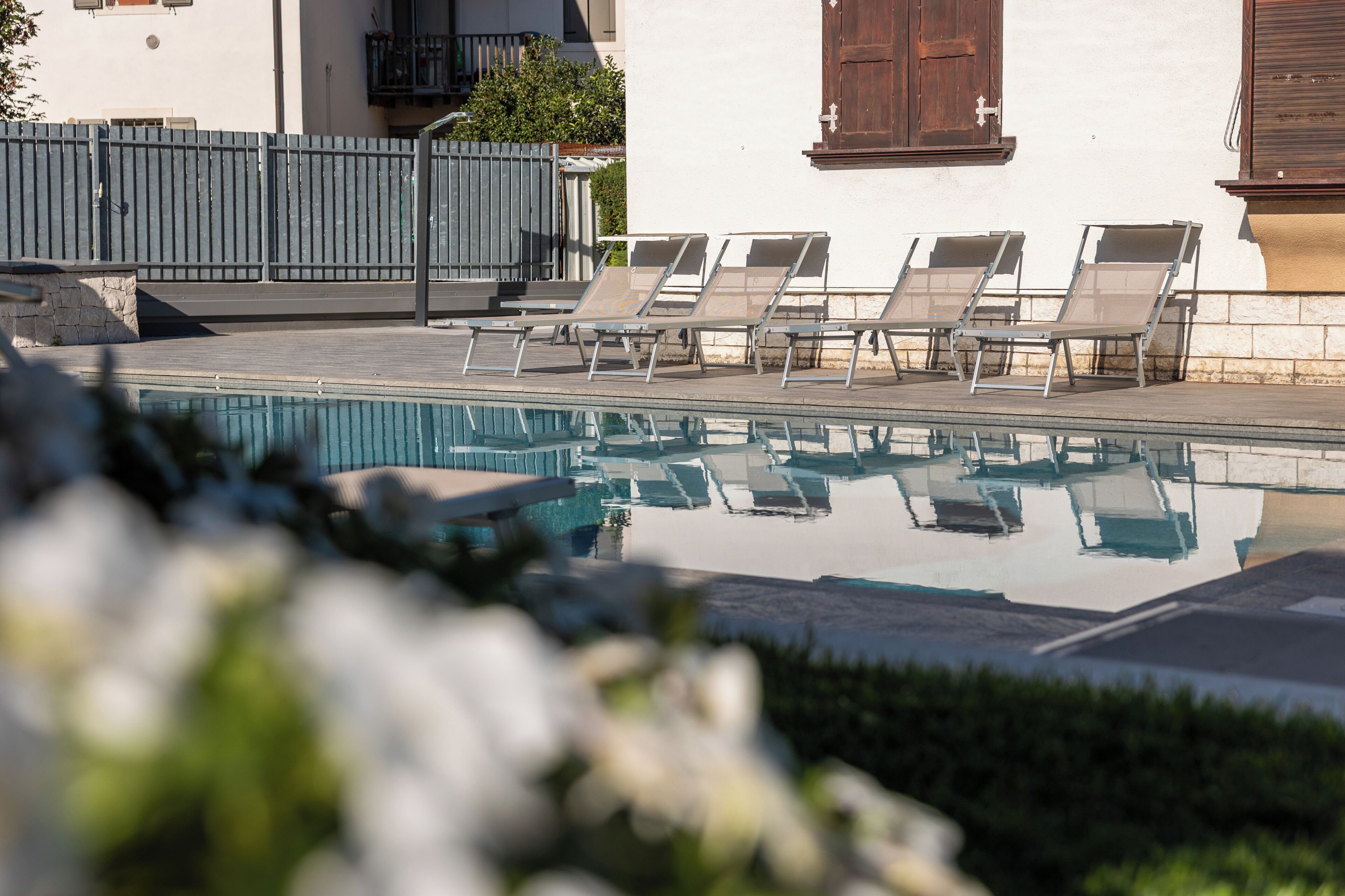 A swimming pool with lounge chairs and a stone wall.