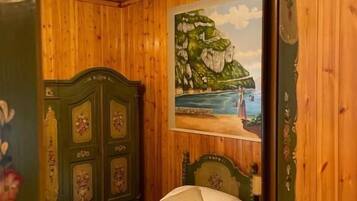 Un dormitorio con cabecera de madera, una cama con colchón blanco y un cuadro de una escena costera en la pared.