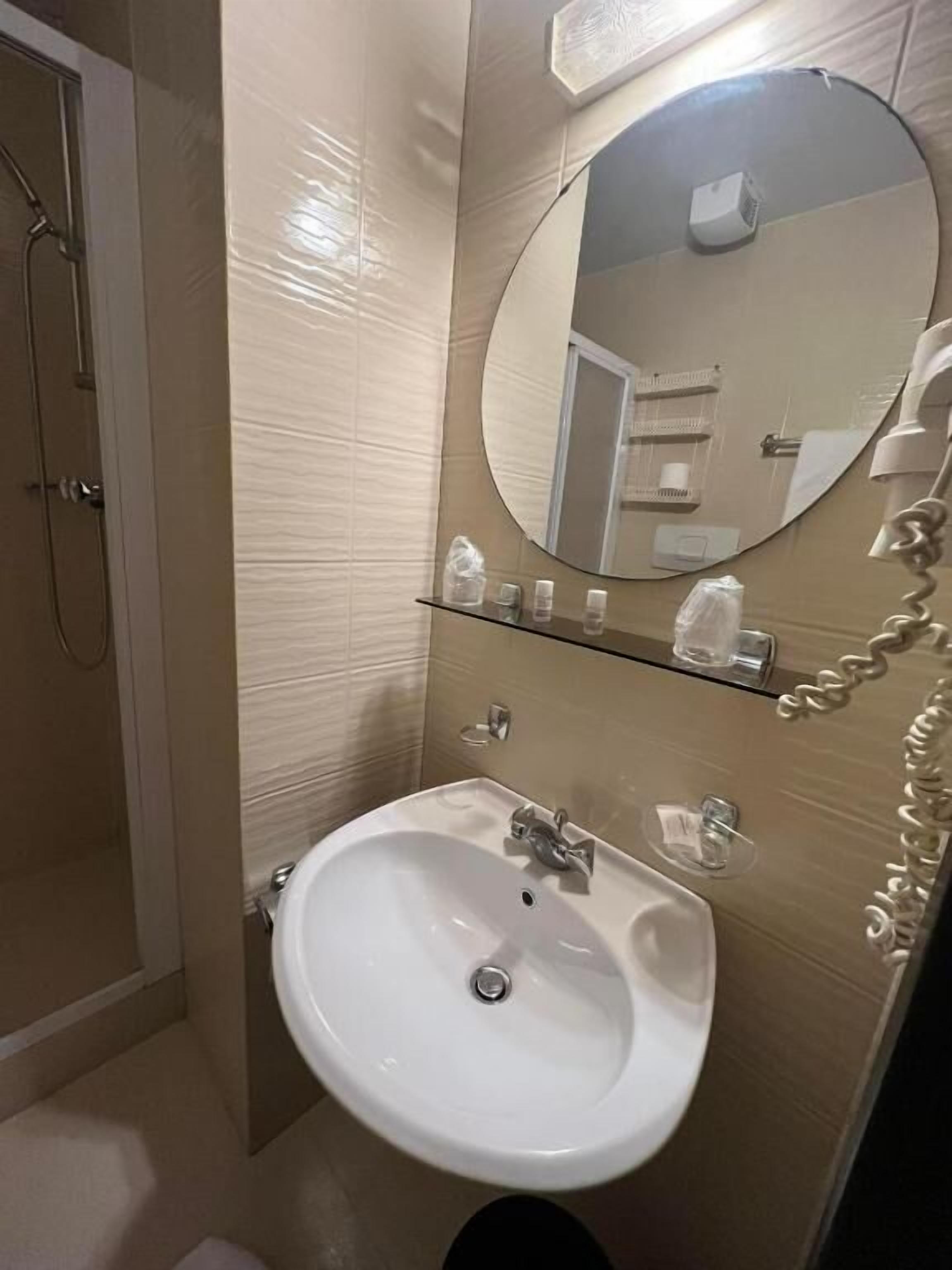 Une salle de bain avec un lavabo blanc, un miroir et une douche.