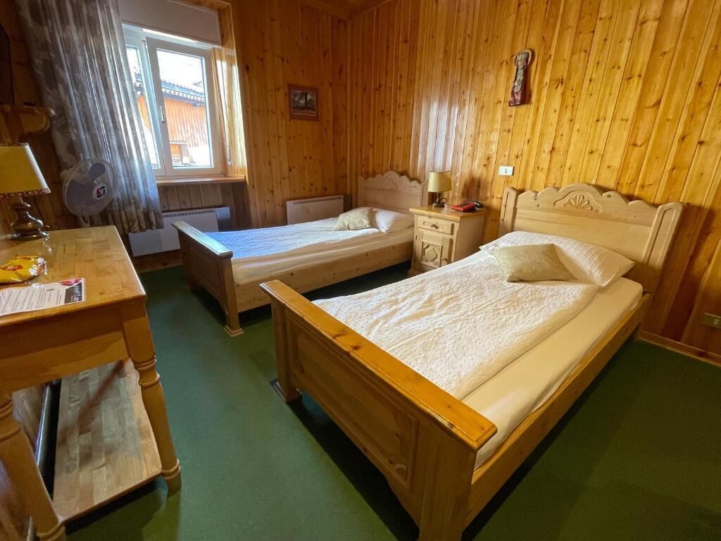 Une pièce en bois avec deux lits, un bureau et une fenêtre avec des rideaux.