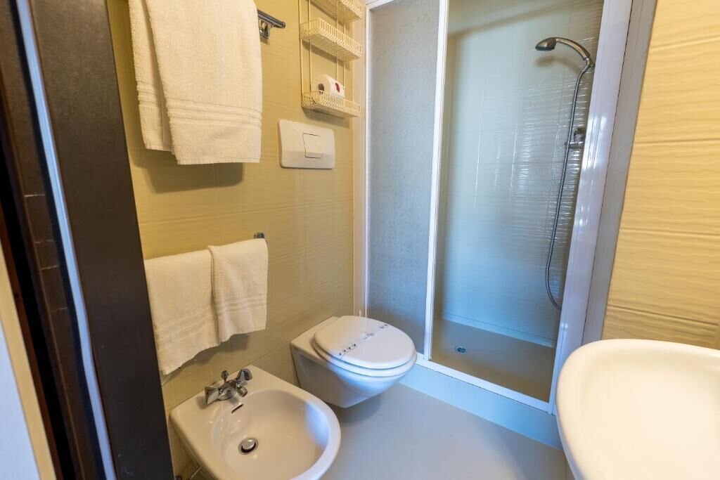 A bathroom with a toilet, sink, and shower.