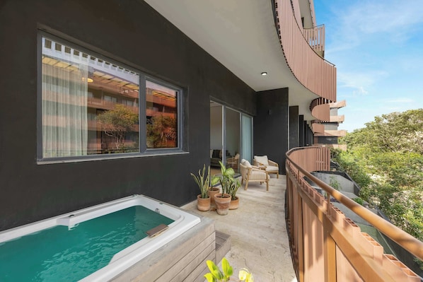 Ein modernes Gebäude mit Balkon, Whirlpool und Kübelpflanzen.