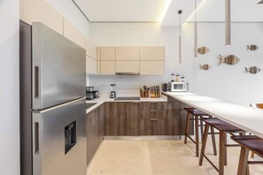 Eine moderne Küche mit Edelstahlgeräten, Holzschränken, einer langen Arbeitsplatte und Barhocker.