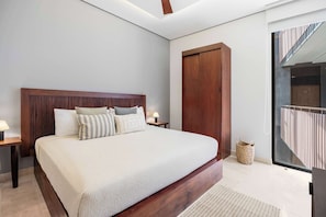 Ein Schlafzimmer mit einem großen Bett, einem Holzkopfende, Nachttischen mit Lampen, einer großen Holztür und Blick auf einen Balkon.