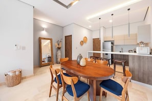 Eine moderne Küche mit einer zentralen Kochinsel, einem Holzespeise-tisch und blauen Stühlen sowie einem eingebauten Kühlschrank.