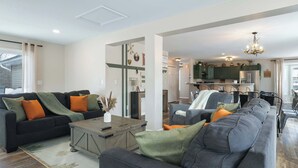 En moderne stue med en modulsofa, et sofabord og et spiseområde med et køkken i baggrunden.