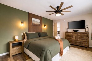 A bedroom with a bed, a wooden dresser, a television, and a ceiling fan. - Nerf Rm | Hot Tub | Theater | Mini-Golf | Bowling (Blakeslee)