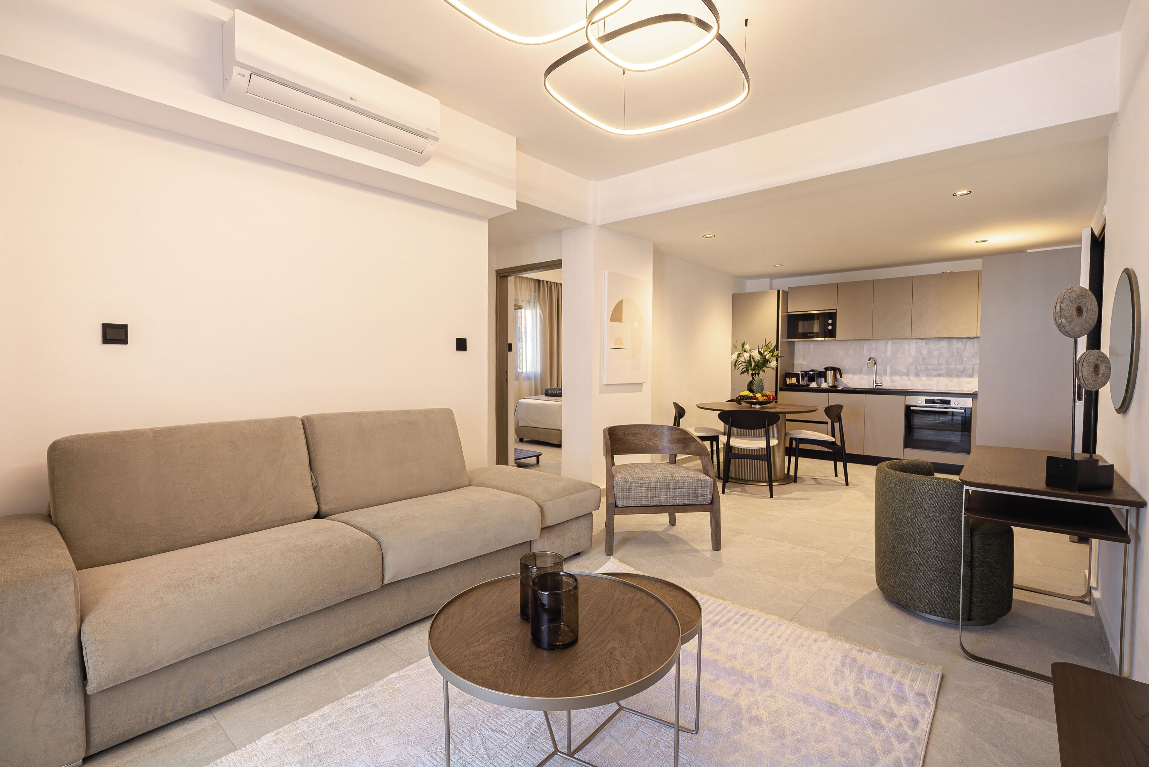 Una sala moderna con un sofá, una mesa de centro redonda y un comedor con sillas y una mesa.