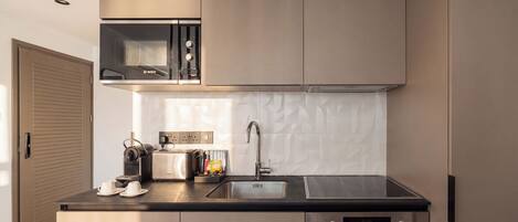 Una cocina moderna con horno integrado, cafetera y lavamanos.