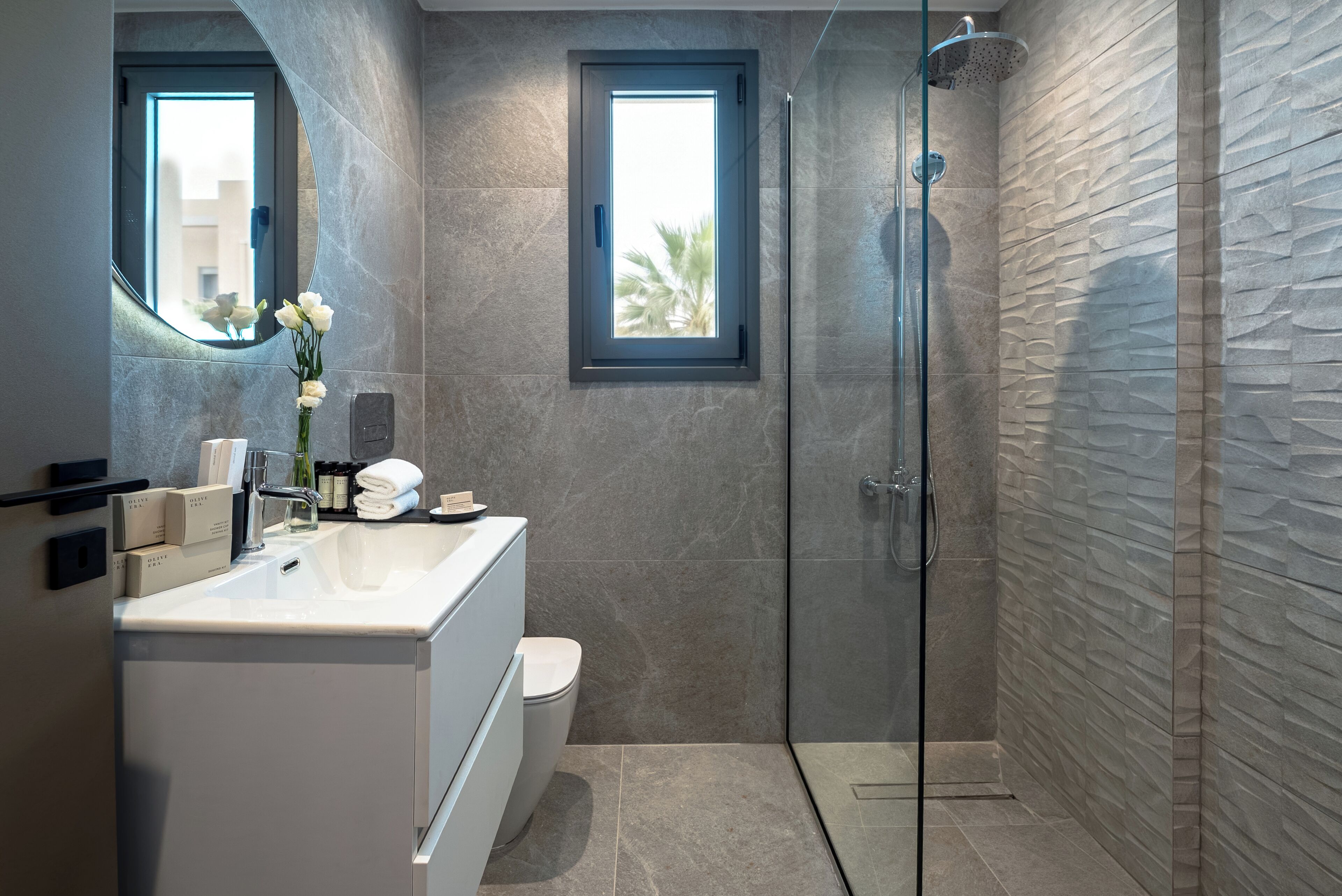 A modern bathroom with a glass shower enclosure, a vanity with a sink, and a toilet.