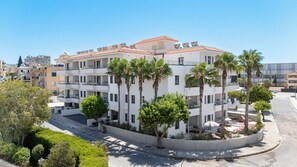 Un edificio de varios pisos con balcones, palmeras y cielo despejado.