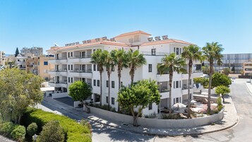Un edificio de varios pisos con balcones, palmeras y cielo despejado.