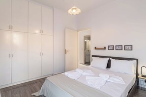 Une chambre d’hôtel avec un lit, une armoire blanche et une porte donnant sur une salle de bain.