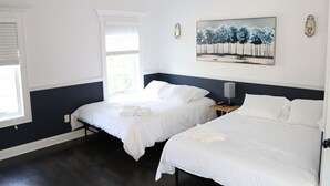 Une chambre d’hôtel avec deux lits, une fenêtre, un tableau et une table de chevet.
