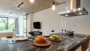 A modern kitchen with a marble countertop, a loaf of bread, a plate of grapes, and a wine glass. - Portal Arévalo in Palermo by Magno | 21 (Buenos Aires)
