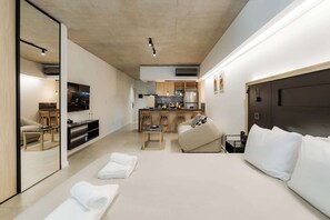 A modern hotel room with a sofa, a dining area, and a kitchen in the background. - Portal Arévalo in Palermo by Magno | 11 (Buenos Aires)