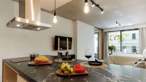 A modern kitchen with a black countertop, a built-in range hood, and pendant lighting. - Portal Arévalo in Palermo by Magno | 12 (Buenos Aires)