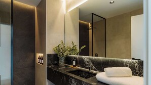 A modern bathroom with a marble sink, a mirror, a towel, and a plant. - Portal Arévalo in Palermo by Magno | 12 (Buenos Aires)
