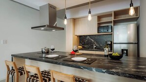 A modern kitchen with a marble countertop, built-in appliances, and pendant lighting. - Portal Arévalo in Palermo by Magno | 41 (Buenos Aires)