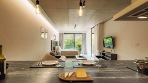 A modern kitchen with a marble countertop, a dining area with a table set for two, and a bedroom with a bed and a TV. - Portal Arévalo in Palermo by Magno | 41 (Buenos Aires)