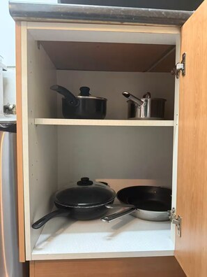 A kitchen cabinet with two shelves, each holding a pot and a pan. - Flat, Arthur Seat view, walking distance to Castle (Edinburgh)