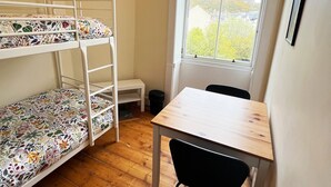 A bunk bed with floral bedding, a wooden table, a black chair, and a window with a view of trees and buildings. - Flat, Arthur Seat view, walking distance to Castle (Edinburgh)