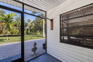A room with a large sliding glass door, a statue, and a view of a garden with palm trees. - La Maison at Alva Oaks Farm- A quiet and serene getaway nestled among old oaks! (Alva)