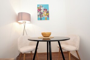 A room with a round table, two chairs, a lamp, and a wall-mounted painting. - Cozy 1-Bedroom Apartment with Easy Access to Vienna’s Old Town #4of4 (Vienna)