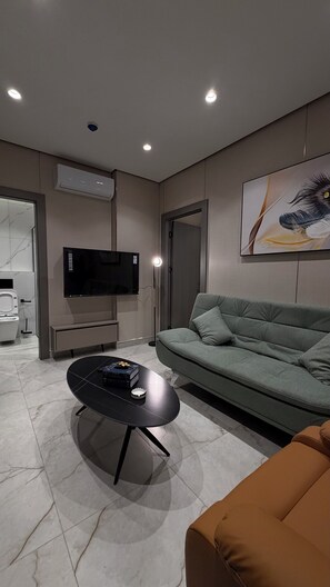 A modern living room with a flat-screen TV, a sofa, a coffee table, and a painting on the wall. - 006 Tara-jre Jabal Al Lweibdeh With Stunning View (Amman)