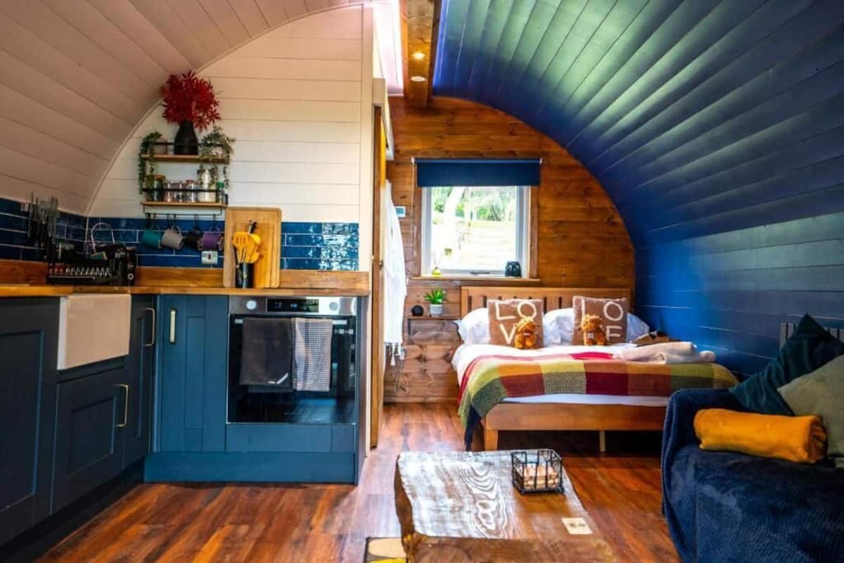 Una habitación pequeña y acogedora con cocina, cama y ventana.