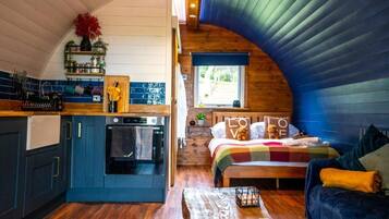 A compact, cozy room with a kitchen, a bed, and a window.