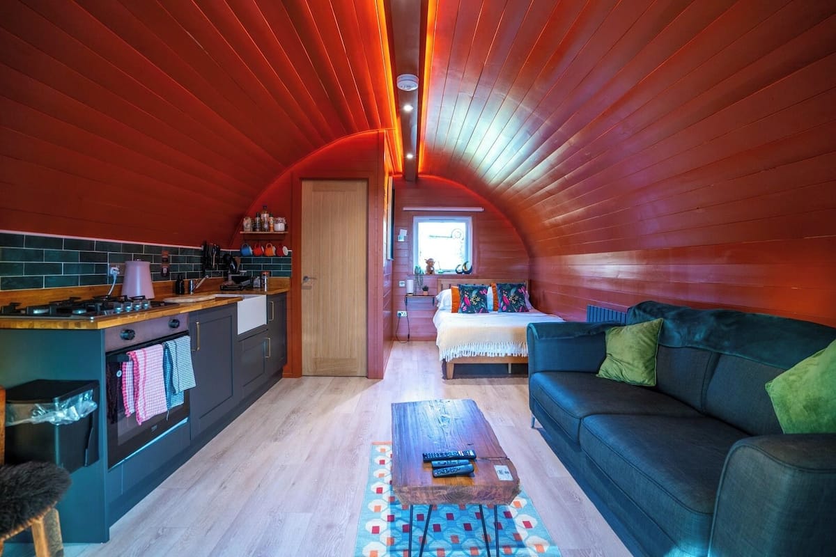 Un interior compacto y acogedor con cocina, comedor y sala de estar con sofá y mesa de centro.