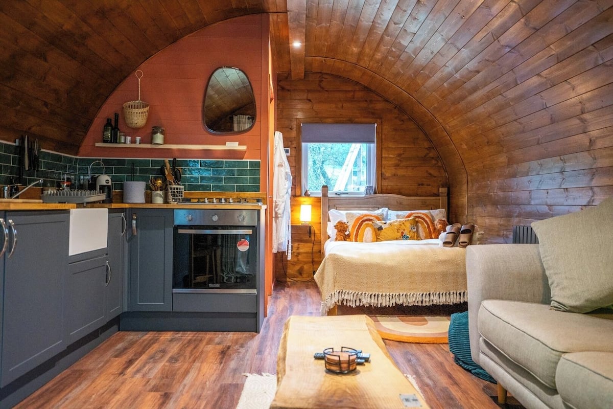 Acogedor interior de cabaña con cocina, comedor y un dormitorio.