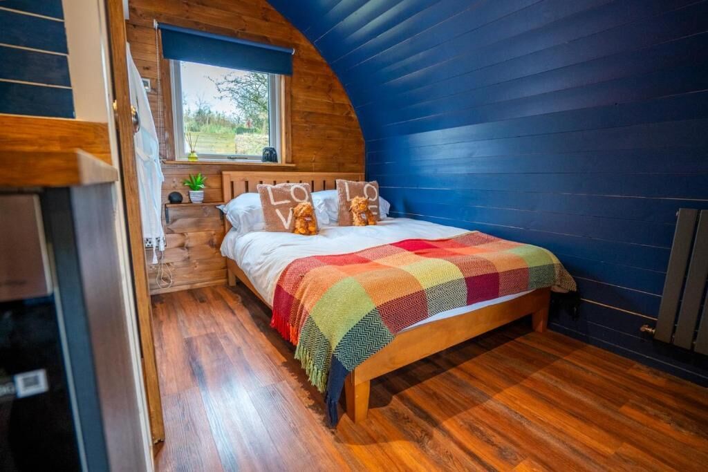 A cozy bedroom with a wooden bed, a colorful blanket, and pillows with 'LOVE' text.