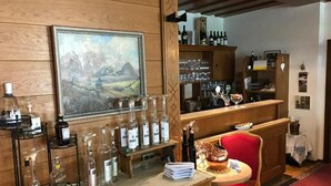A bar area with bottles, glasses, and a painting. - Gasthof Sprenger (Sillian)