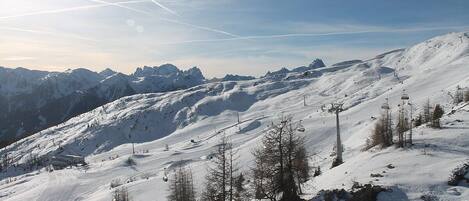 A snow-covered mountain slope with ski lifts and a clear sky.