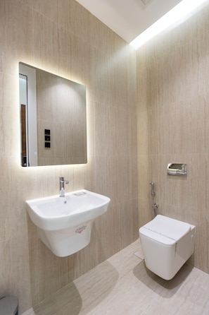 Un baño moderno con un lavamanos blanco, un espejo y un inodoro.