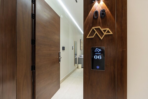 Entrada a una habitación de hotel con puerta de madera, teclado digital y señal con número.
