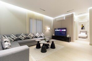A modern living room with a grey sofa, black and white patterned cushions, a flat-screen TV, and a coffee table with black bases. - Elegant Medina Stay Perfect for Families (Madinah)