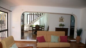 A living room with a sofa, chairs, a dining table, and a staircase leading to another room. - Country House 'Quinta Da Eira' with Private Pool, Wi-Fi and Air Conditioning (Lagoa)