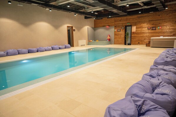A swimming pool with a tiled floor, a wooden wall, and a reception desk. - Vama54 Family Resort&SPA (Tarlungeni)