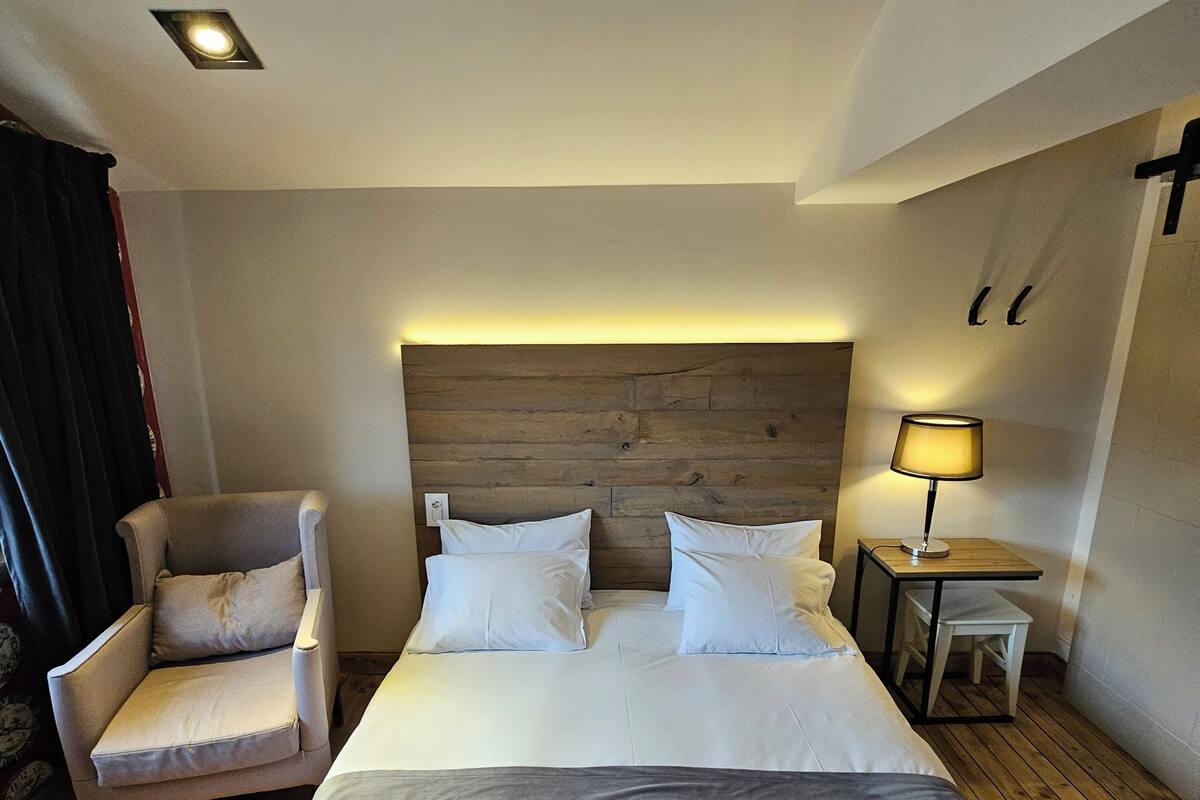 Ein Hotelzimmer mit einem Bett, einem Sessel, einem Nachttisch und einer Lampe.
