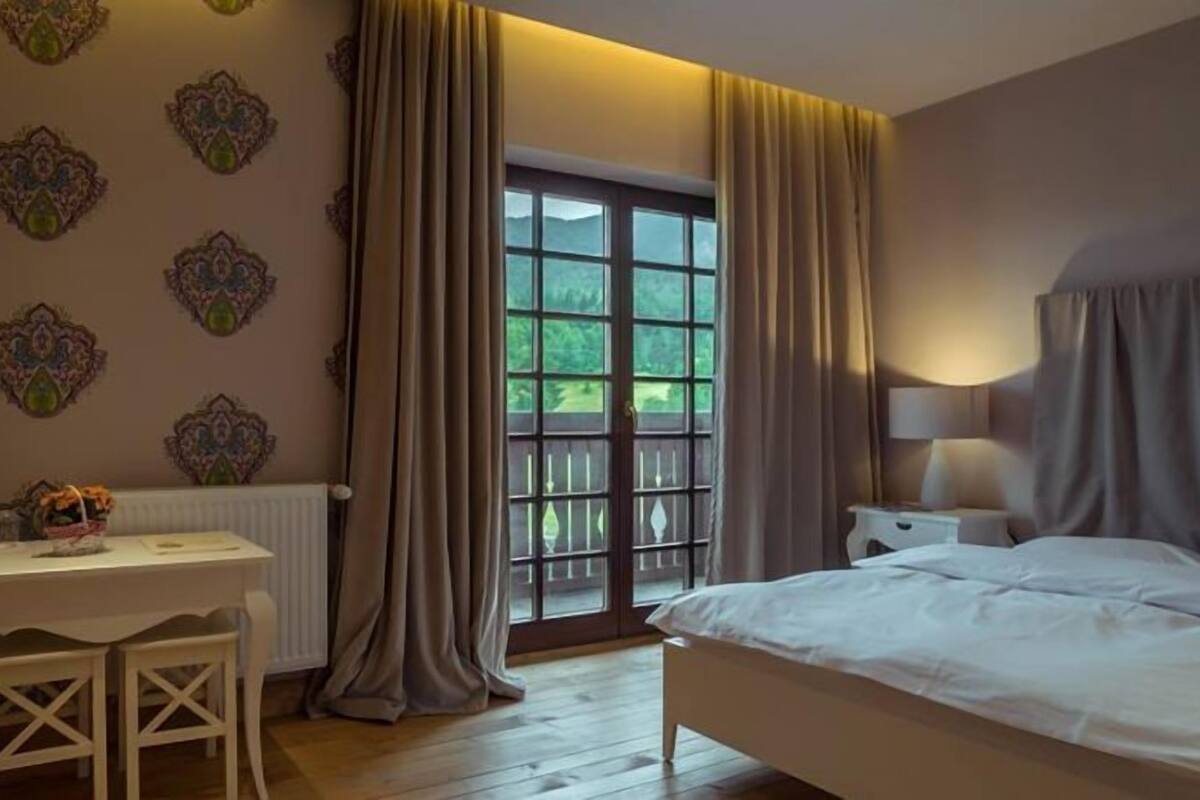 Ein Schlafzimmer mit einem Bett, einem Schreibtisch und einem Fenster mit Vorhängen.