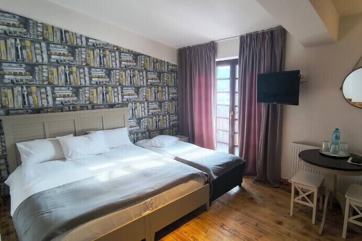 Ein Schlafzimmer mit einem Bett, einem Schreibtisch, einem Stuhl, einem Fernseher und einer Wand mit strukturiertem Wandpapier.