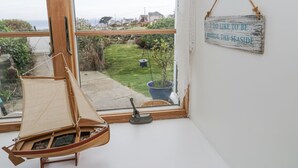 Una habitació amb una maqueta de veler, vista al mar i un rètol que diu 'm'agrada estar a la vora del mar'.