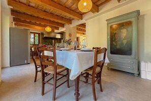 Un coin repas avec une table ronde, des chaises en bois et un grand meuble surmonté d’un tableau.
