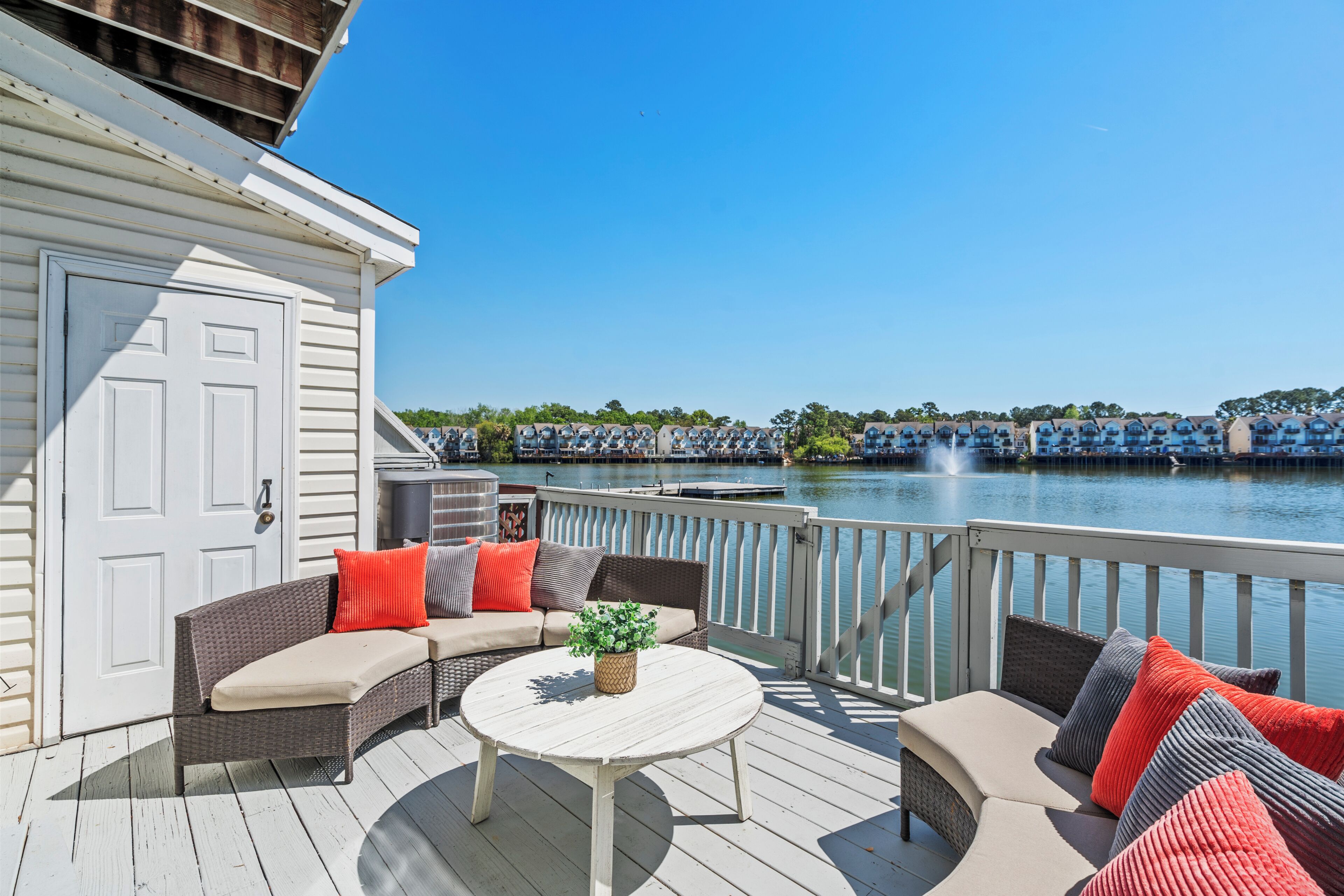 A deck with a sofa and a table, overlooking a body of water with boats.