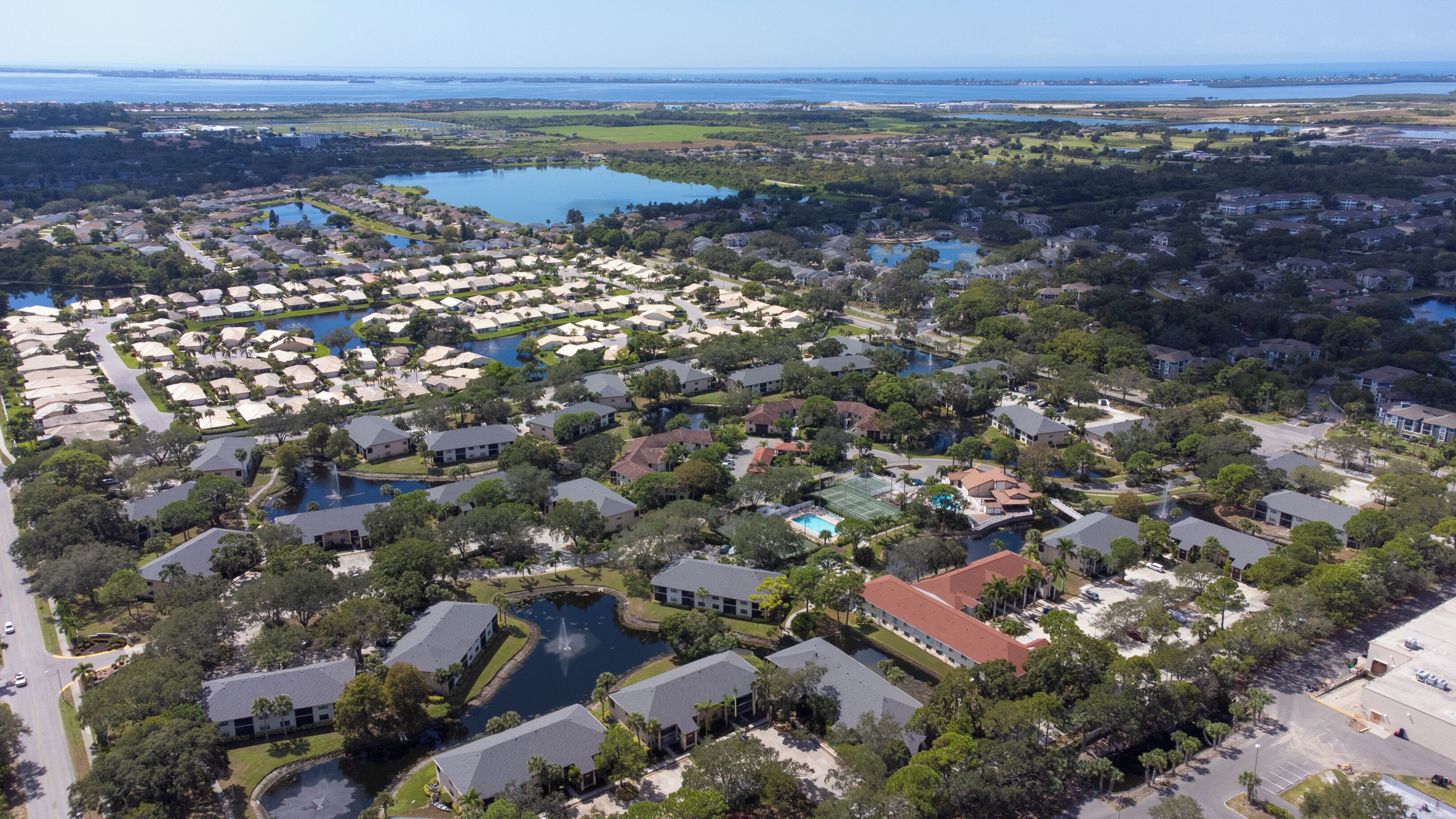 An aerial view of a residential area with houses, a large body of water, and a golf course.