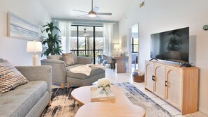 Ein Wohnzimmer mit Sofa, Sessel, Couchtisch, Fernseher und Deckenventilator.